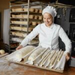Woman baker or pastry cook making fresh bread in local bakery: