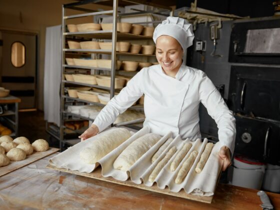 Woman baker or pastry cook making fresh bread in local bakery: