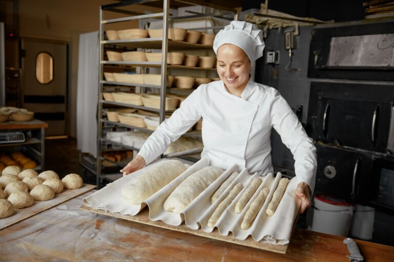 Woman baker or pastry cook making fresh bread in local bakery: